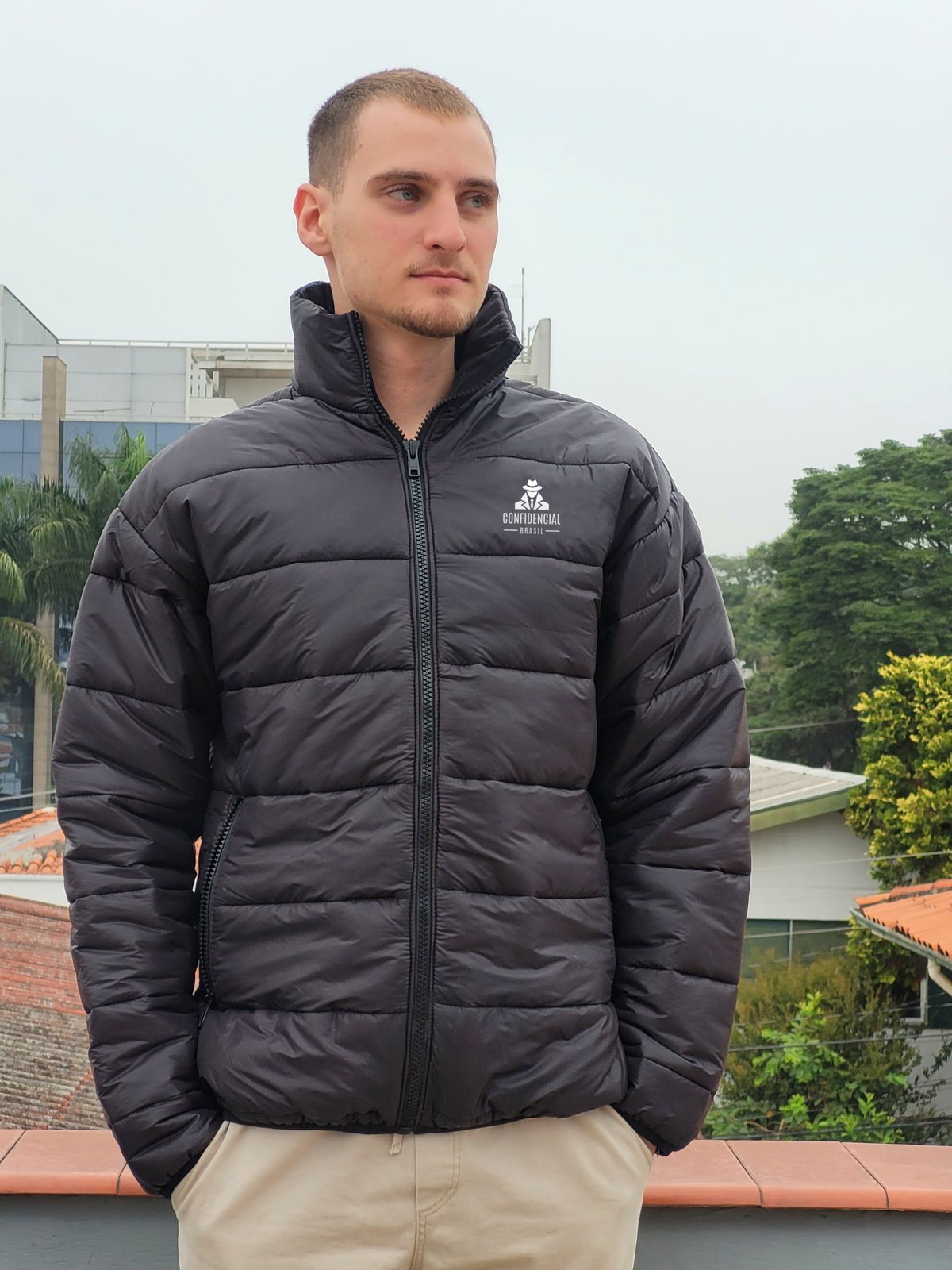 Modelo vestindo jaqueta puffer preta com o logo Confidencial Brasil bordado no peito